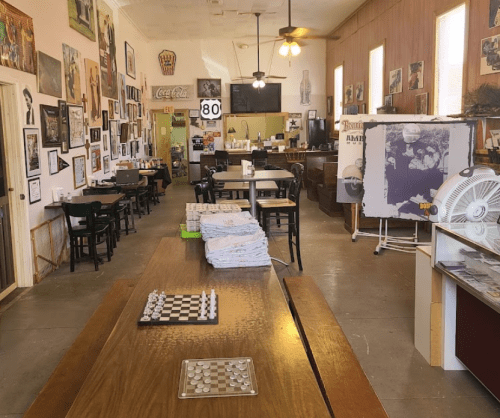 A cozy diner interior with tables, a chessboard, and walls adorned with vintage photos and memorabilia.