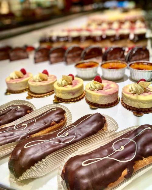 A display of assorted desserts, including chocolate eclairs, cheesecakes, and custard cups, beautifully arranged.