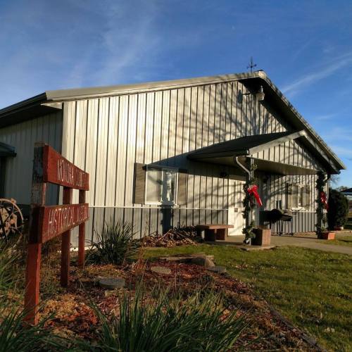 A metal building with a sign reading "Historical Museum," decorated with holiday wreaths and surrounded by greenery.