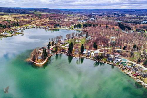 Aerial view of a serene lake surrounded by trees and houses, reflecting the cloudy sky above.