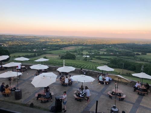 A scenic view of a vineyard at sunset, with outdoor seating under umbrellas and people enjoying the landscape.