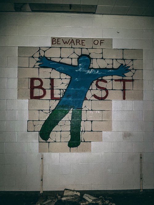 A mural on a wall depicting a blue silhouette breaking through bricks with the text "BEWARE OF THE BEAST."