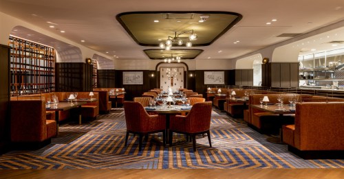 Elegant restaurant interior featuring cozy booths, tables set for dining, and modern decor with warm lighting.