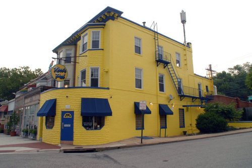A bright yellow building with blue awnings and a fire escape, located at a street corner.