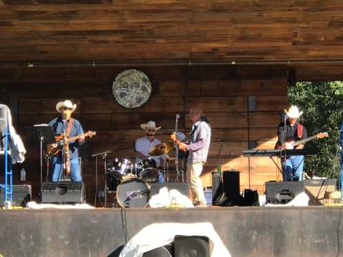 A country band performs on stage, featuring four musicians in cowboy hats with guitars, drums, and a keyboard.