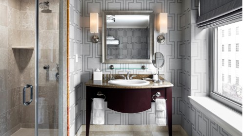Modern bathroom featuring a glass shower, stylish sink, and elegant decor with patterned wallpaper.