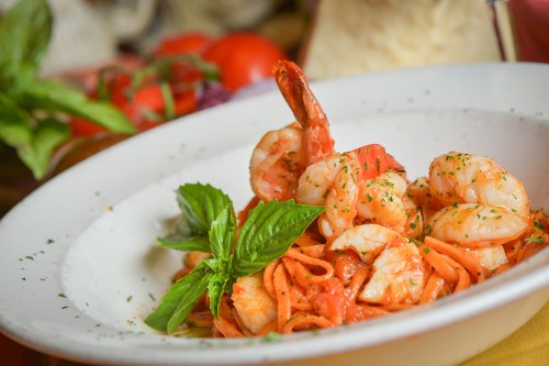 A plate of shrimp pasta garnished with fresh basil, served in a rich tomato sauce.
