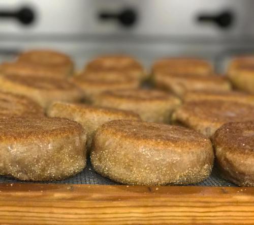 Freshly baked, golden-brown muffins lined up on a wooden tray, dusted with sugar.