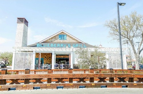 Exterior of Blueberry's Grill, featuring a wooden deck and a clear blue sky.