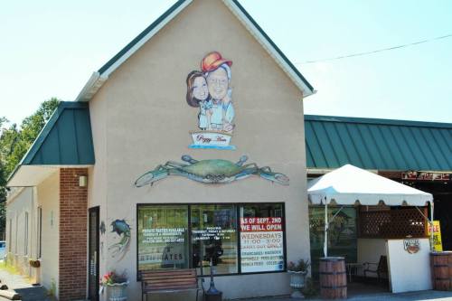 A building with a mural of a man and woman, featuring a large crab design on the wall and outdoor seating.