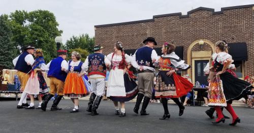 A group of dancers in traditional costumes perform together at an outdoor event, showcasing cultural heritage.