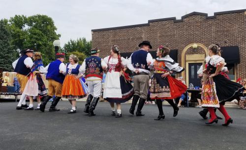 A group of dancers in traditional costumes perform together outdoors, showcasing vibrant colors and cultural heritage.