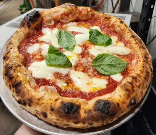 A freshly baked pizza with a golden crust, topped with tomato sauce, mozzarella cheese, and fresh basil leaves.