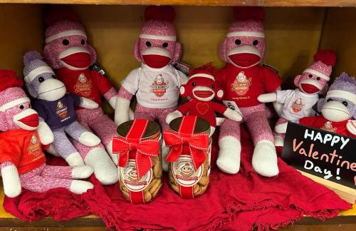 A display of colorful sock monkey plush toys with jars of cookies, decorated for Valentine's Day.
