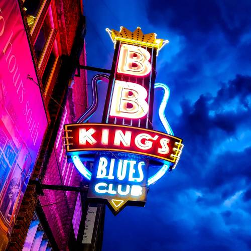 Neon sign for B.B. King's Blues Club illuminated against a dramatic evening sky.