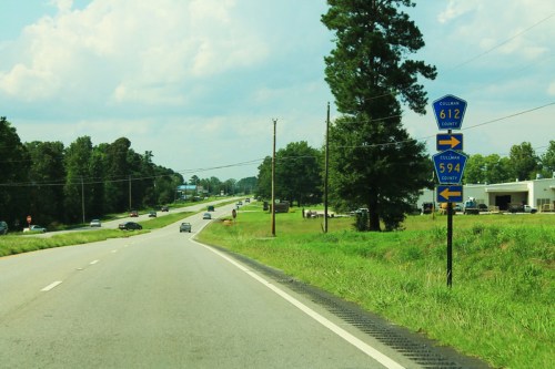 Road sign indicating directions to Cullman County 612 and 594, with a view of a highway and green landscape.