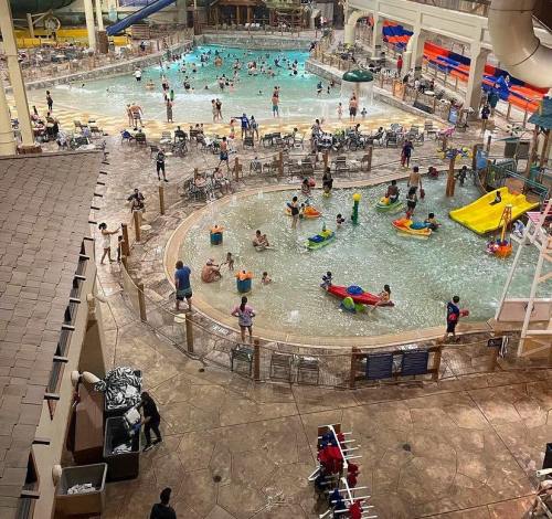 A busy indoor water park with pools, slides, and families enjoying various water activities.