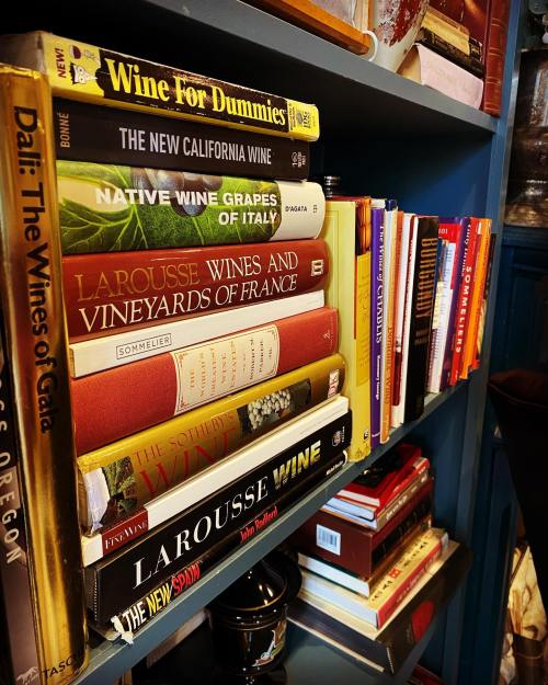 A bookshelf filled with various wine-related books, including "Wine for Dummies" and "Larousse Wine."