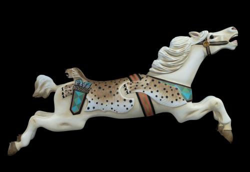 A decorative carousel horse in mid-gallop, featuring a spotted design and colorful accents on a black background.