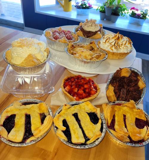 A variety of delicious desserts, including pies, cupcakes, and tarts, displayed on a wooden table.