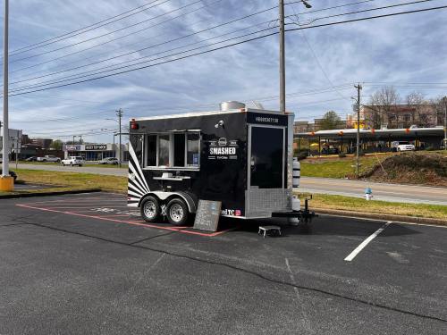 A black food truck named "Smashed" parked in a lot, with a menu board outside and power lines in the background.