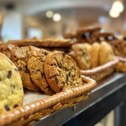 A close-up of a basket filled with various cookies, including chocolate chip and oatmeal varieties.