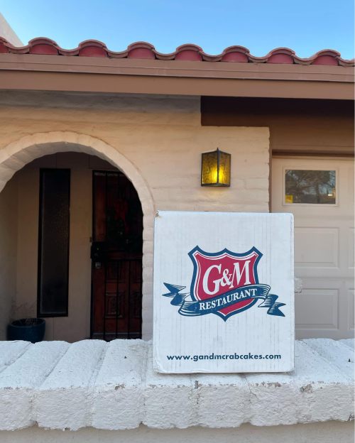 Sign for G&M Restaurant displayed outside a building with a light fixture and door visible in the background.