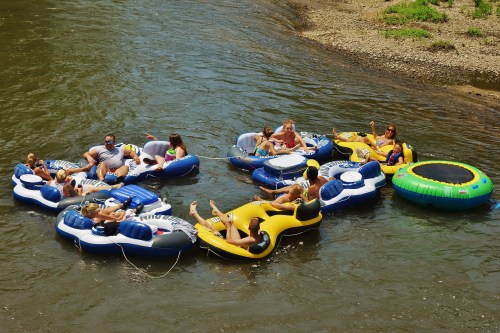 A group of people relaxes on colorful inner tubes in a river, enjoying a sunny day.