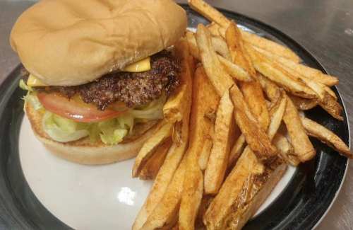 A cheeseburger with lettuce, tomato, and fries on a plate.