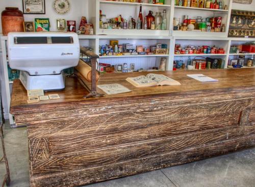 A vintage wooden counter with an old cash register, surrounded by shelves filled with various jars and canned goods.