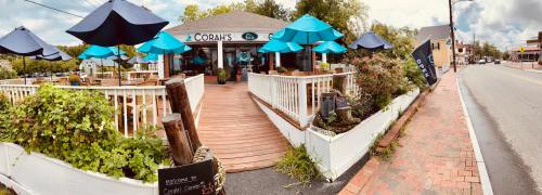 Exterior view of Corah's restaurant with blue umbrellas, wooden deck, and a welcoming entrance along a street.