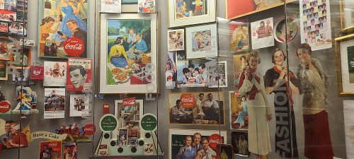 A display of vintage Coca-Cola advertisements and memorabilia, featuring colorful posters and nostalgic images.