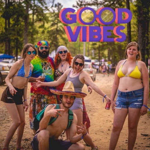 A group of six people in colorful outfits poses outdoors, with "GOOD VIBES" text above them.