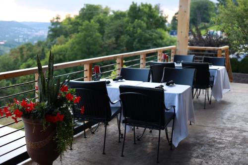 Outdoor dining area with tables set for guests, surrounded by greenery and a scenic view.