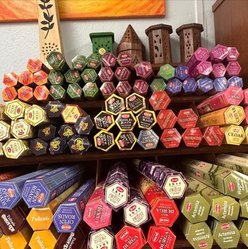 A colorful display of various incense sticks arranged in hexagonal boxes on a wooden shelf.