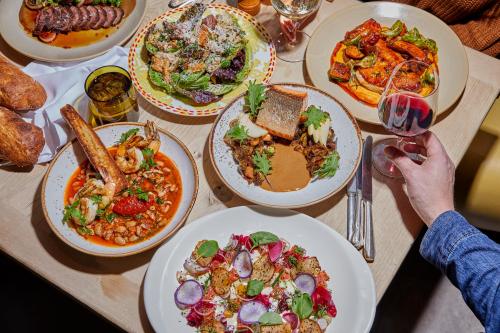 A table spread with various dishes, including seafood, salads, and meats, alongside drinks and bread.