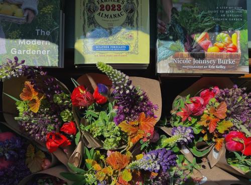 Colorful flower bouquets arranged with gardening books on display.