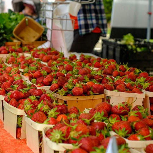 Baskets of fresh strawberries displayed at a vibrant farmers market.