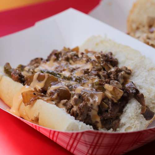 A sandwich filled with seasoned ground beef, sautéed peppers, and melted cheese on a soft hoagie roll.