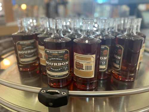 A collection of bourbon whiskey bottles arranged on a circular display.