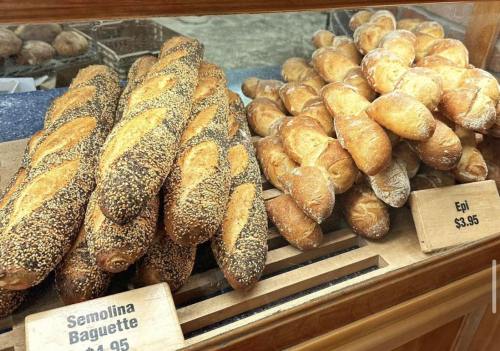 A display of two types of bread: semolina baguettes with seeds and epi loaves, both freshly baked.