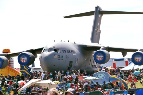 A large U.S. Air Force cargo plane at an outdoor event, with a crowd of people enjoying the festivities nearby.