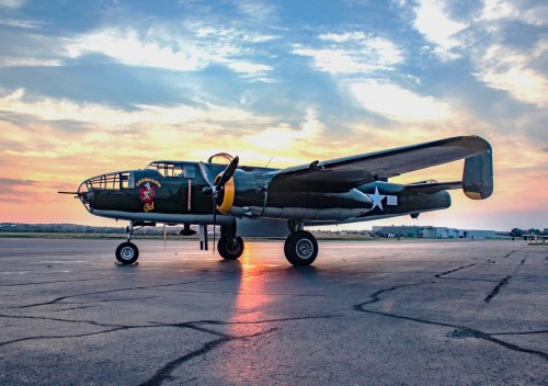 A vintage military aircraft on an airstrip at sunset, showcasing its detailed design and vibrant colors.