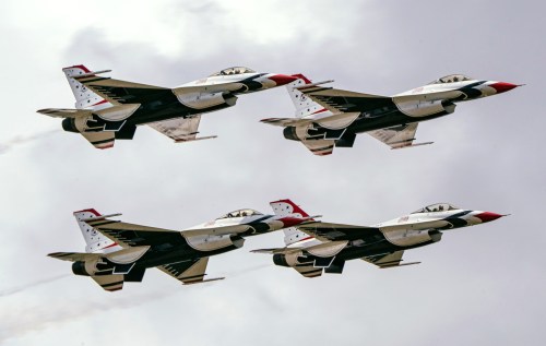 Four fighter jets flying in formation against a cloudy sky.