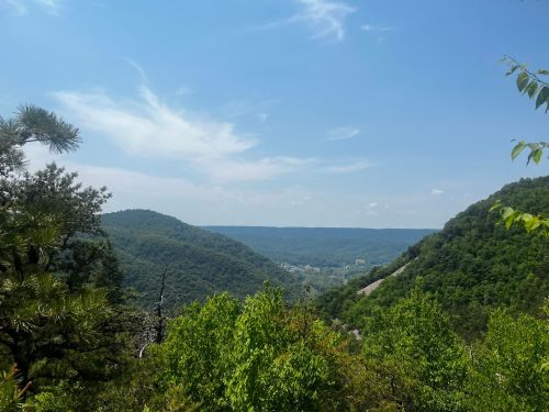 A scenic view of green mountains and valleys under a blue sky with scattered clouds.