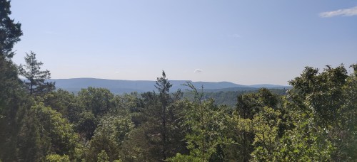 A scenic view of rolling hills and lush green trees under a clear blue sky.