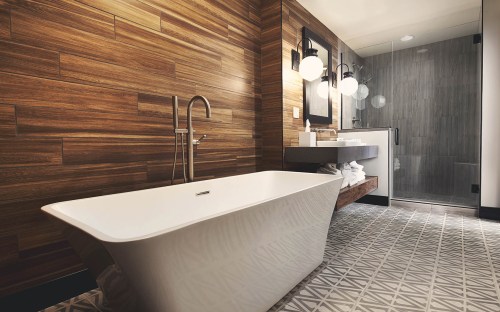 Modern bathroom featuring a freestanding tub, wooden accent wall, and a glass shower with stylish fixtures.