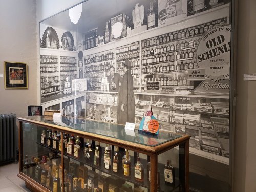 A vintage black-and-white photo of a store interior with shelves of products and a display case in the foreground.