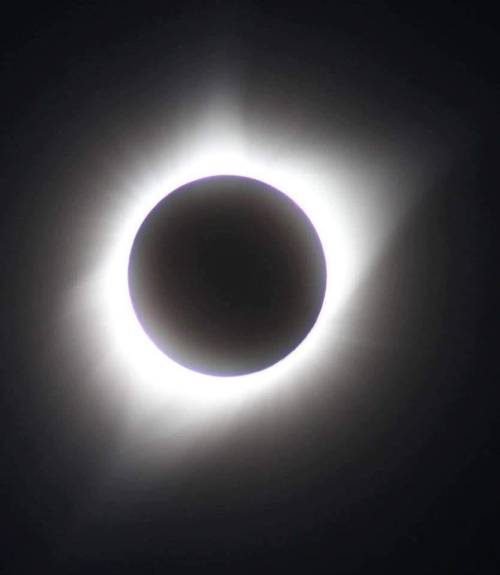 A solar eclipse with a darkened sun surrounded by a glowing halo of light.