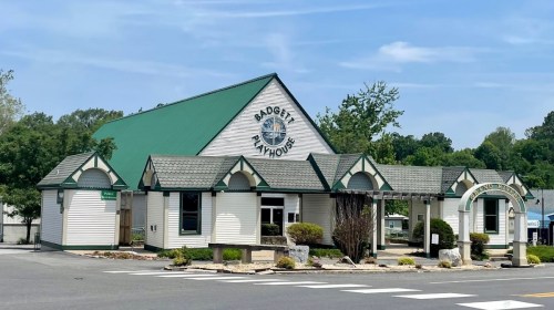A white building with a green roof and decorative trim, featuring a sign for a seafood restaurant.